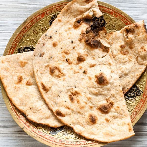 Three pieces of Virasat Indian Cuisine's naan bread on a decorative gold and red plate.